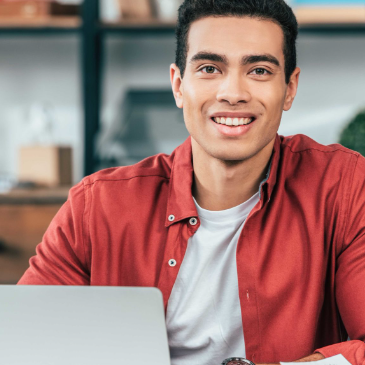 Image of smiling student sitting at laptop computer.